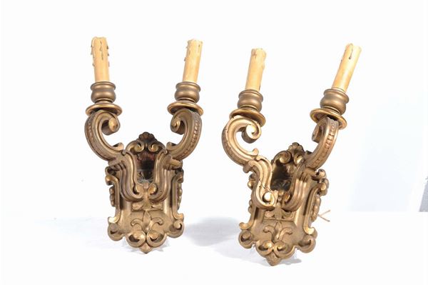 Coppia di appliques in stile legno intagliato e dorato a due luci