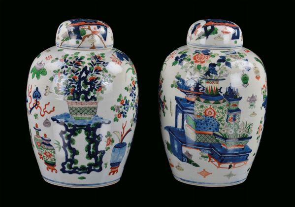 Pair of porcelain potiches with cover, China, Qing Dynasty, 19th century polychrome decoration with vases, tables and vegetable elements, post marked Kangxi,  h cm 36