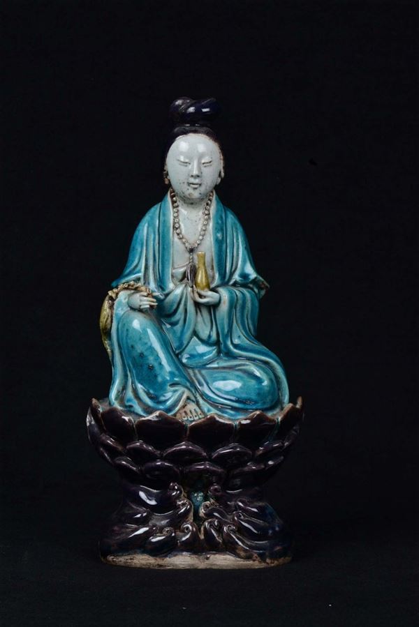 Sitting Guanyin on a polychrome porcelain lotus flower, China, Qing Dynasty, Kangxi Period (1662-1722) light blue and aubergine tone, h cm 33