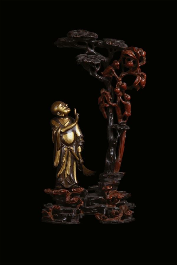 Gilt bronze sculpture representing oriental character with vegetation and monkeys, China, Qing Dynasty, 18th century, mounted on a richly sculpted wooden base, cm 25x12