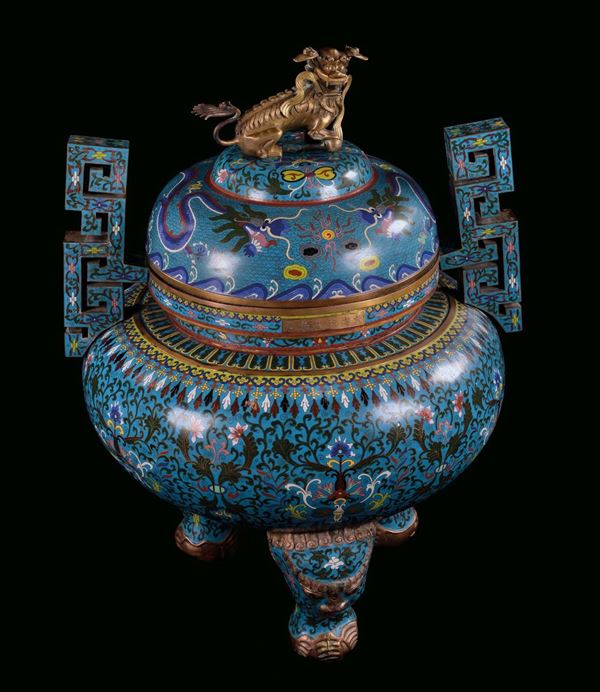 Monumental gilt bronze and cloisonné enamel censer, China, Qing Dynasty, 19th century. Ovoid body on three feet with elephant heads, large Greek handles, decorations with stylized vegetable motives on light blue background, gilt bronze Pho dog on the cover, six-character post Qianlong, cm 73x65x100