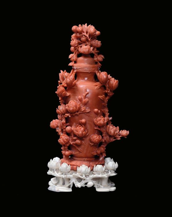 A red coral sculpture representing a vase with floral shoots, China, Qing Dynasty, 19th centuryIvory base sculpted with flowers and leaves