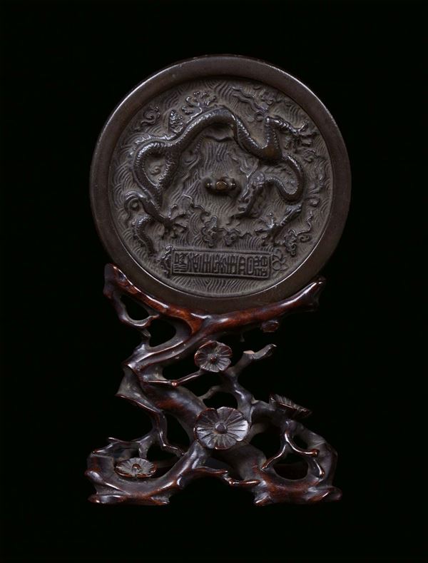 A silver plated bronze mirror with carved wood base, China, Ming Dynasty, 16th century