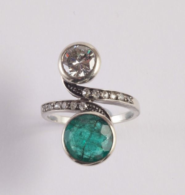 A diamond and emerald cross over design ring