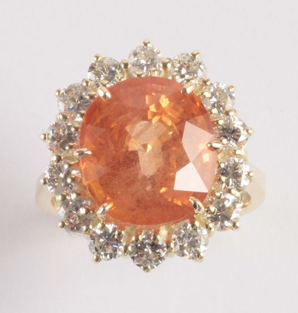 An orange sapphire and diamond cluster ring