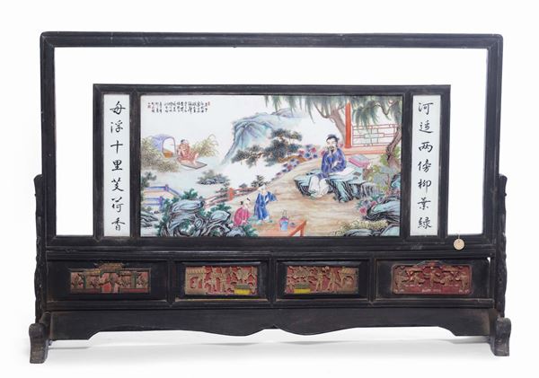 A large porcelain plaque representing figures within a landscape with ideograms on a wooden base, China, Republic, 20th century