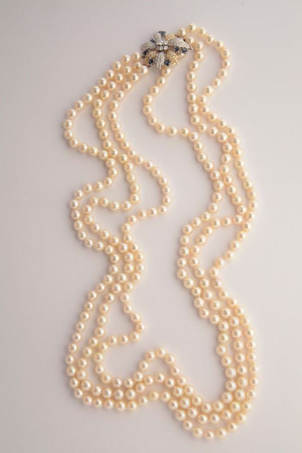 A cultured pearl necklace with a gold, shappire and diamond clasp
