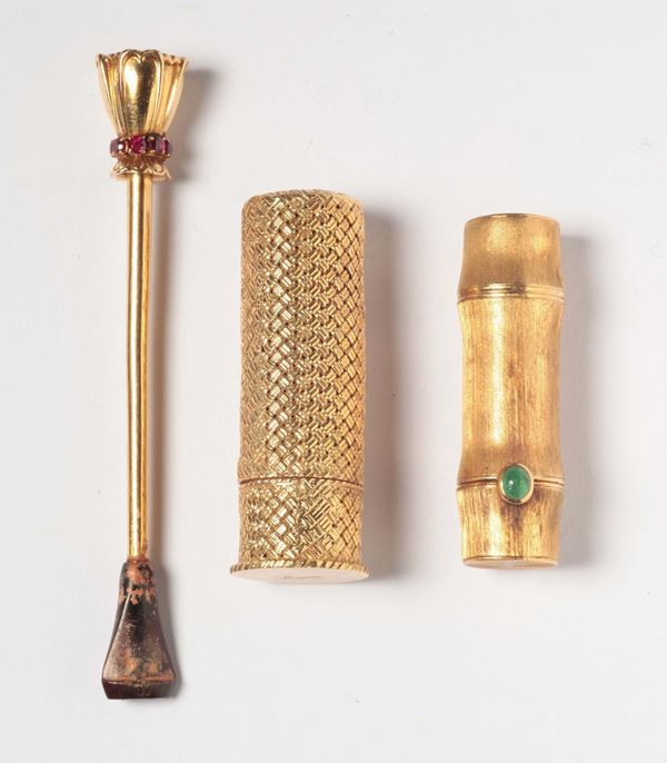 A cigarette holder and two gold lipstik case