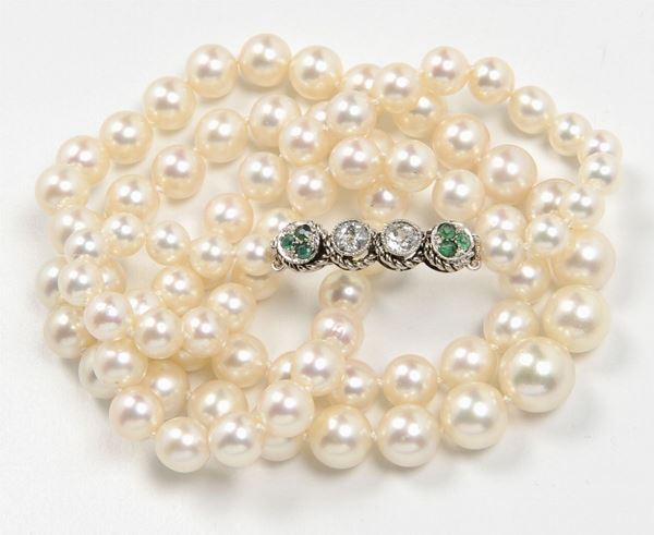 A cultured pearl necklace. A gold, diamond and emerald clasp