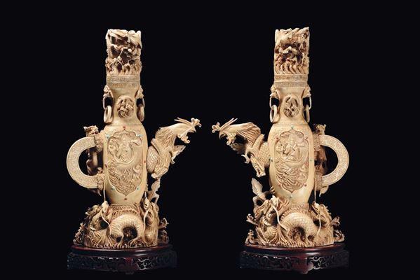 A pair of carved ivory sculpture on a wooden base with animals in relief, China, Qing Dynasty, late 19th century