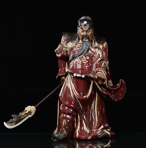 A monochrome iron red flambé glazed stoneware warrior with sword, China, Qing Dynasty, late 19th century