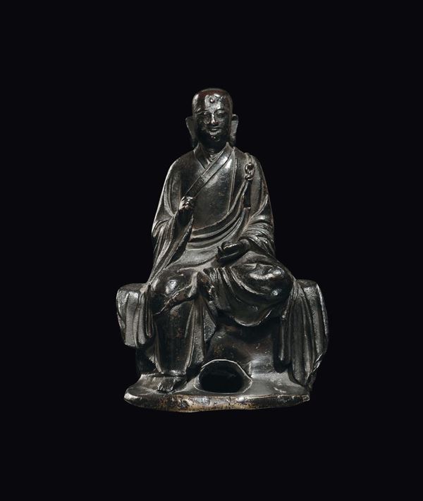 A bronze sitting Lama on a rock, China, Ming Dynasty, late 17th century