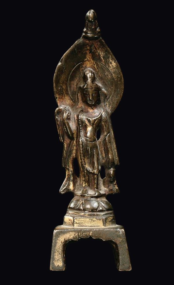 A small partially gilt bronze standing Buddha, China, probably Wei Dynasty (386-534)
