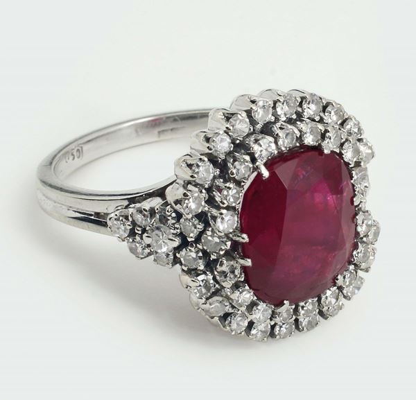 A ruby and diamond ring. The central cushion-shaped ruby, weighing 5,10 carats. Accompanied by a report from R.A.G. Torino, stating that the ruby is of Burmese (Myanmar) origin and no evidence of heat and clarity enhancements. Report number