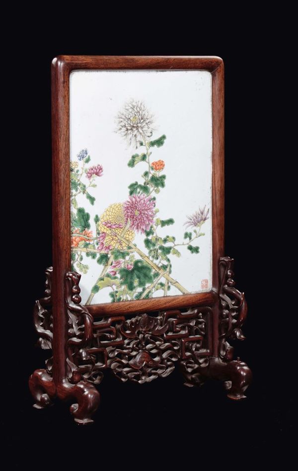 A polychrome porcelain plaque with flowers on a carved wood support, China, 20th century