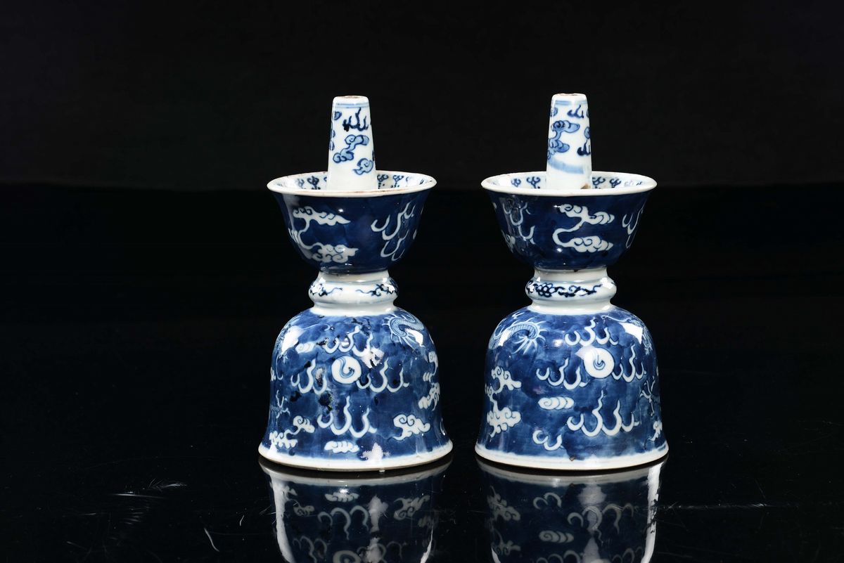 Cina, Coppia di candelieri in porcellana bianca e blu con raffigurazioni di draghi tra le nuvole,...