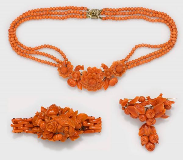 Lotto composto da bracciale in corallo, pappagallo inciso; collana e spilla con motivi di fiori e frutta in corallo mediterraneo