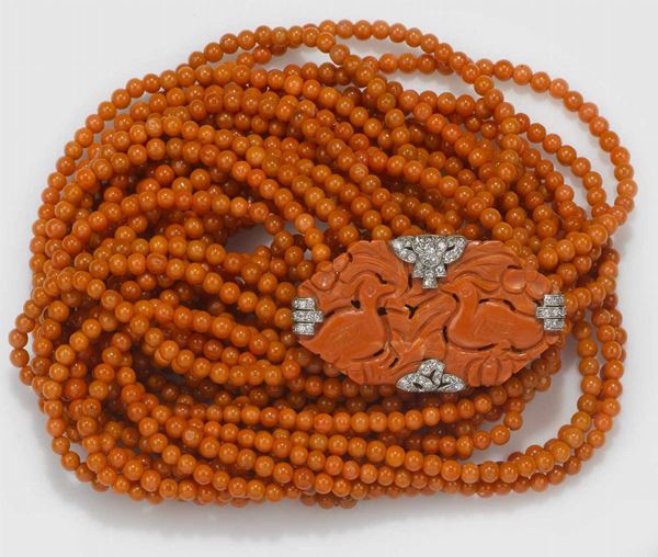 Sautoir composto da sette fili di corallo aranciato guarnita da una spilla art deco in corallo e diamanti