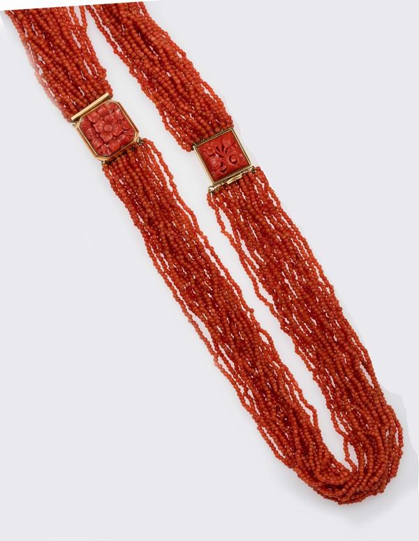 A multi-strand coral necklace with a two carved coral clasp