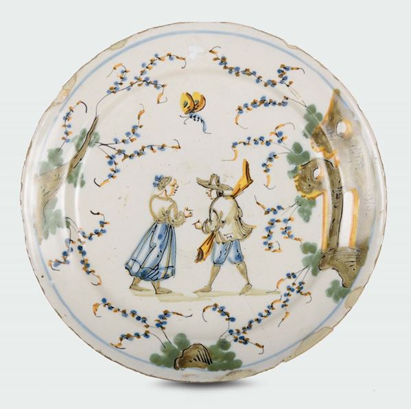 A polychrome majolica plate with two figures and ruins, fortress mark, Ferro Guidobono manufacture, Savona, early 18th century