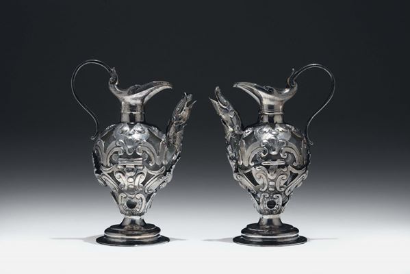 Coppia di ampolle da messa in vetro rivestito in argento sbalzato e cesellato. Italia centrale, Roma (?) XVII-XVIII secolo