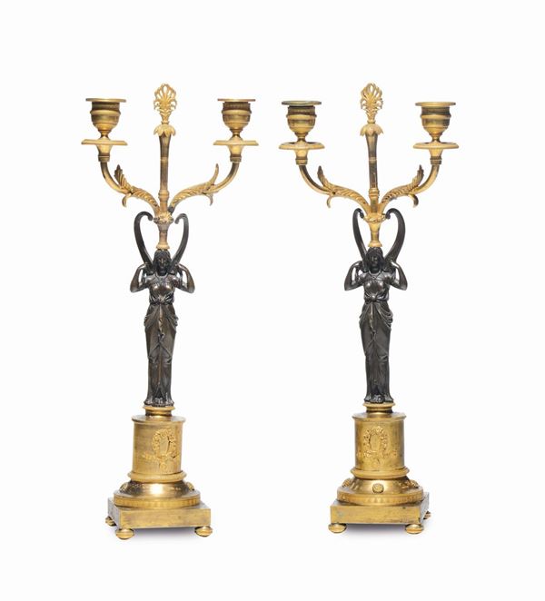 Coppia di candelieri a due luci in bronzo cesellato, dorato e brunito. Francia, epoca Impero, inizio XIX secolo