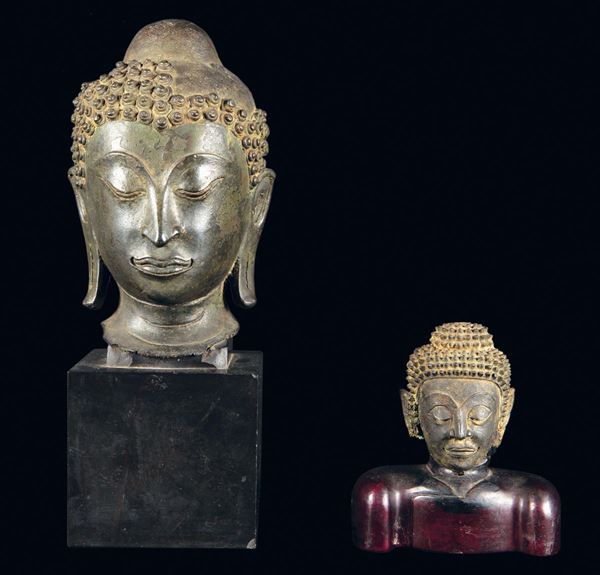 Lotto di due teste di Buddha in bronzo, una con base in marmo nero e una con base in legno, Thailandia, epoca Ayutthaya, XVII secolo