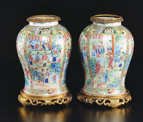 A pair of polychrome enamelled porcelain vases on a gilt bronze base depicting court life scenes, China, Canton, Qing Dynasty, 19th century