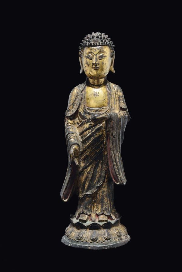 A large semi-gilt bronze figure of standing Buddha with swastica, China, Ming Dynasty, 17th century