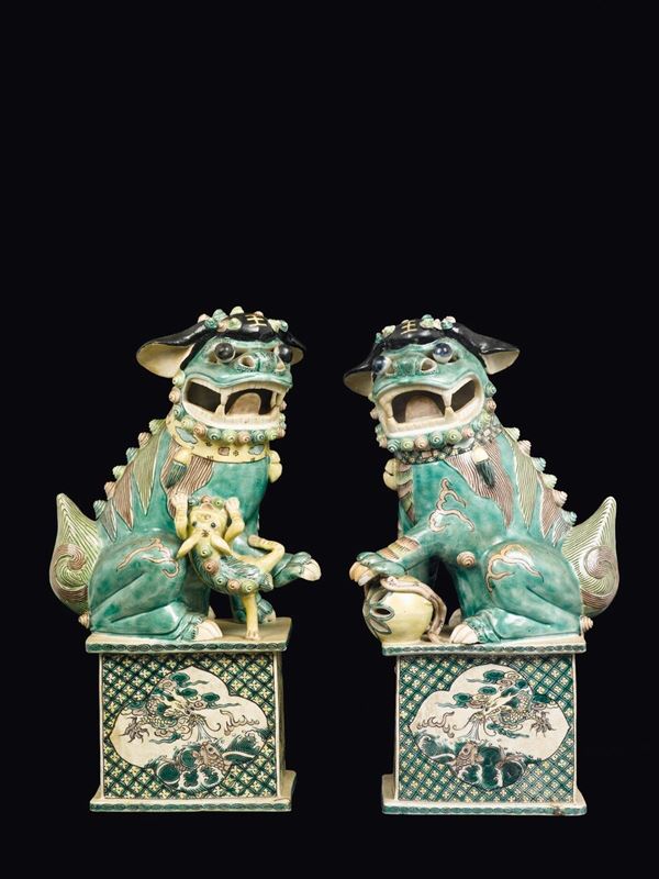 Due cani di Pho in porcellana a smalti policromi con decori naturalistici alla base, Cina, Dinastia Qing, XVIII secolo
