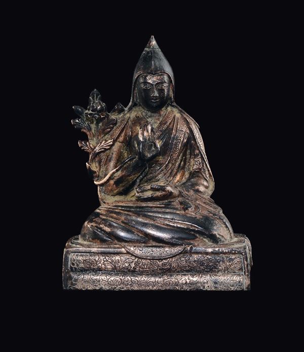 Figura di Lama seduto in bronzo con tracce di doratura con libro in mano, Tibet, XVIII secolo