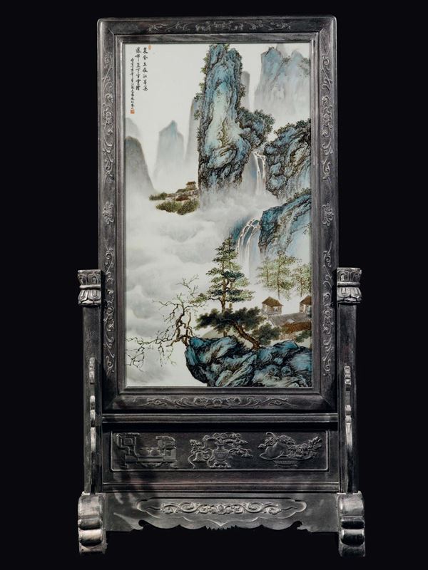 Grande placca in porcellana a smalti policromi raffigurante paesaggio montano con case ed iscrizione sopra stand in legno, Cina, inizio XX secolo