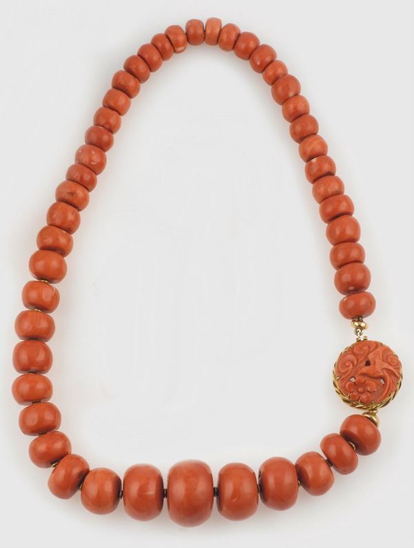 A coral necklace with a carved coral clasp