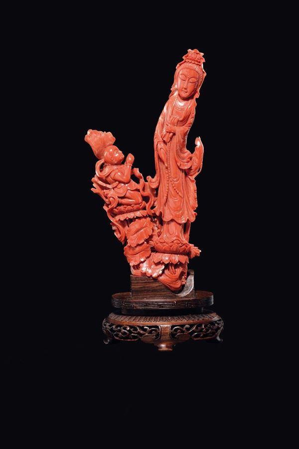 A carved coral Guanyin with praying child on lotus flowers, China, early 20th century