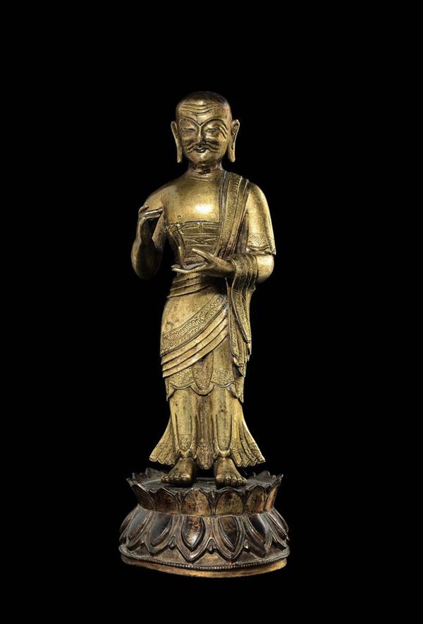 A gilt bronze figure of a standing monk on a double lotus flower, Tibet, 16th century