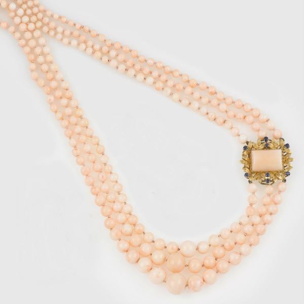 A coral necklace with a gold and sapphire clasp