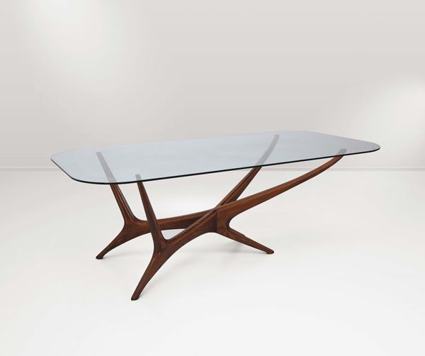 Tavolo con struttura in legno lavorato e piano in vetro.