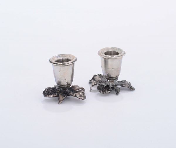 Due piccoli candelabri con base a motivi fogliacei in metallo argentato