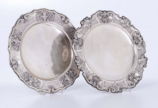 Due piatti in argento con bordo decorato a volute in stile settecento