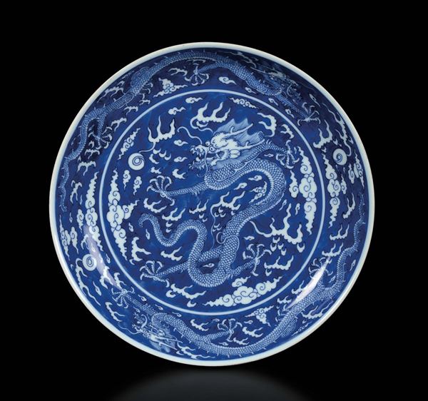 Piatto in porcellana bianca e blu con decoro di draghi tra le nuvole, Cina, Dinastia Qing, marchio e del periodo Qianlong (1736-1795)