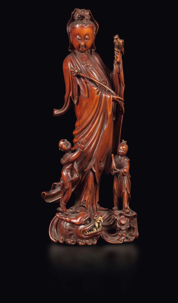 A wooden figure of Guanyin with ruyi and children on a dragon, China, Qing Dynasty, 19th century