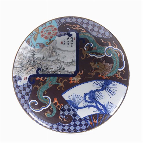 Grande piatto in porcellana con dragone e decoro naturalistico entro riserve con iscrizione, Giappone, XIX secolo
