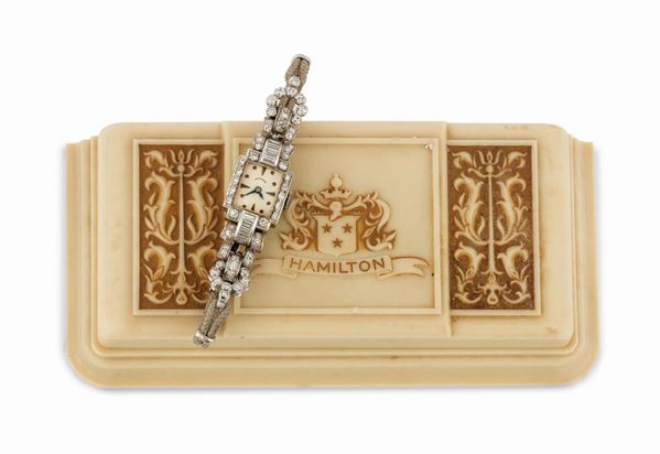 HAMILTON, Diamond Bracelet Watch, case No. 2133546.The square-shaped watch is decorated on the top with round, single- and baguette-cut diamonds, with round, brilliant, single- and baguette-cut diamonds lining the bracelet.  Made circa 1930. Accompanied by the original and  rare bakelite box