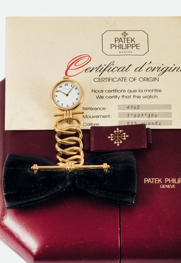 PATEK PHILIPPE, LEATHER BOW, YELLOW GOLD, No. 1607306, case No. 2870567,REF. 4762. Made in a limited edition of 50 pieces for the 150th Anniversary of Patek Philippe in 1989. Very fine and unusual, 18K yellow gold and leather lady's brooch-lapel quartz watch with Patek Philippe yellow gold brooch fitting. Accompanied by the original fitted box, Certificate of Origin, Attestation, the 150th Anniversary Commemorative Medal and booklets.