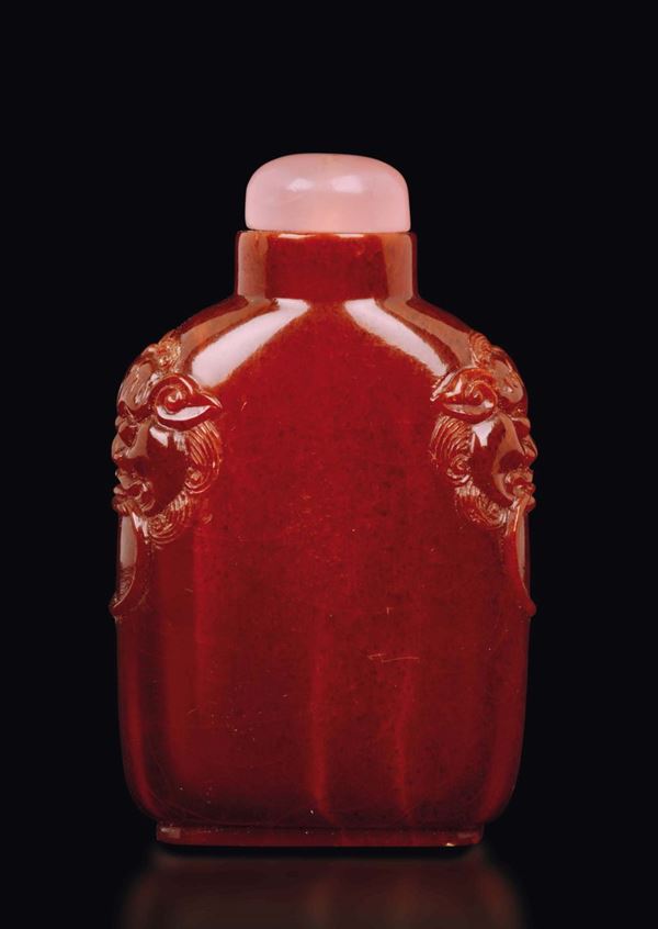 An amber snuff bottle with mask handles, China, Qing Dynasty, 19th century