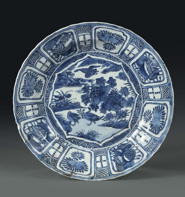 A porcelain plate with a white and blue decoration. The brim is divided into quarters. China, Qing dynasty, 18th century