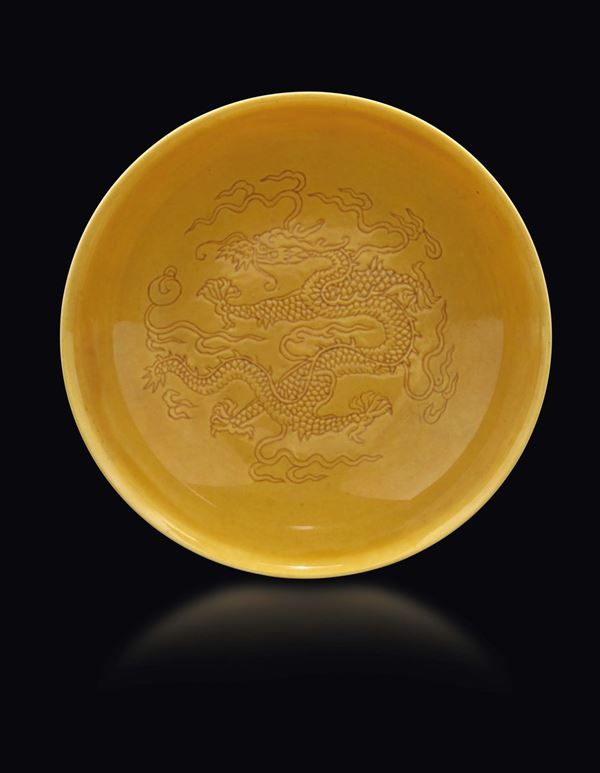 Piatto in porcellana a fondo giallo con decoro graffito di draghi tra le nuvole, Cina, Dinastia Qing, marchio e del periodo Qianlong (1736-1795)