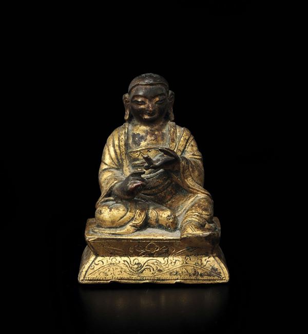 Piccola figura di monaco seduto in bronzo dorato, Tibet, XVII secolo