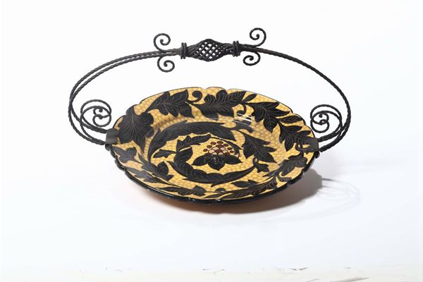 Cestino centrotavola costituito da un piatto in ceramica con montatura in ferro battuto coeva d’epoca. Marcato CAS anni 20/30