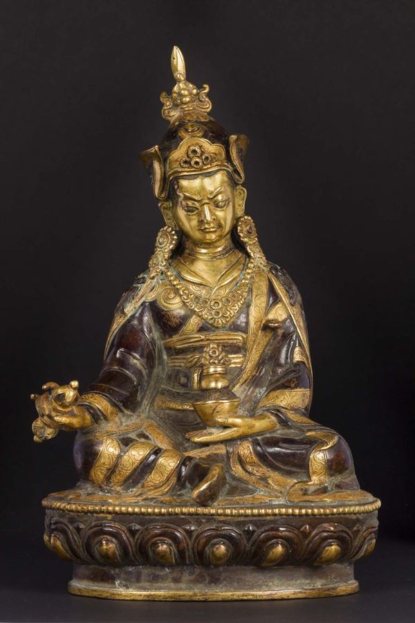 Figura di Padmasambhava in bronzo dorato e brunito seduto su fiore di loto con in mano dorje e coppa, Tibet, fine XVII secolo
